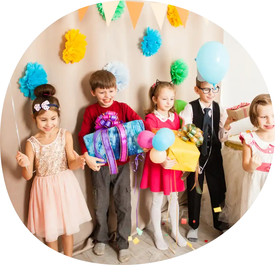 Barn på en fest som håller i gåvor och ballonger.