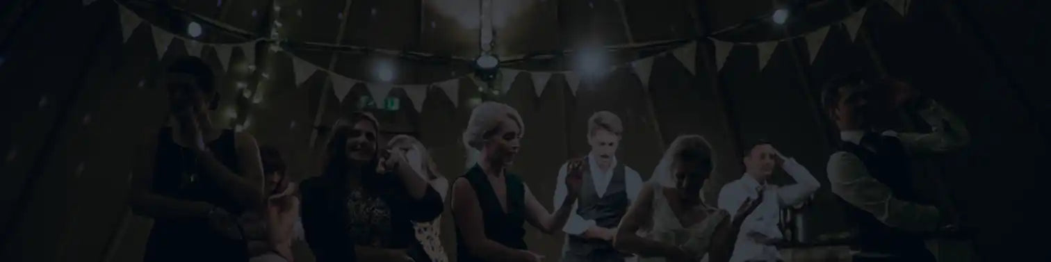 En mörk, svagt upplyst samling av människor i vad som verkar vara en festlig miljö.